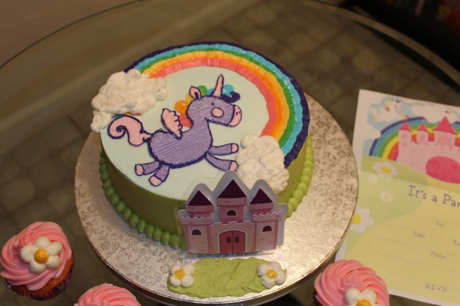Close view of the cake top: the piped rainbow, buttercream clouds, and the unicorn